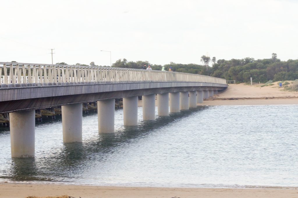 A overexposed image of a concrete bridge crossing between two beaches